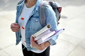 woman wearing blue denim jacket holding book