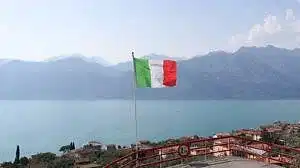 a flag flying on top of a hill next to a body of water