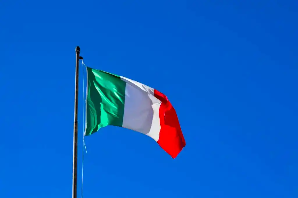 Italian flag flying against a vibrant blue sky, symbolizing national pride and identity.